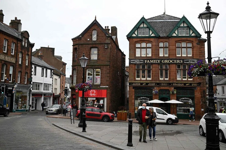 VARIAN YANG MEMBIMBANGKAN: Pejalan kaki di Penrith di Cumbria, barat laut England, memakai pelitup selepas penularan sejenis varian membimbangkan (VoC). - Foto AFP
