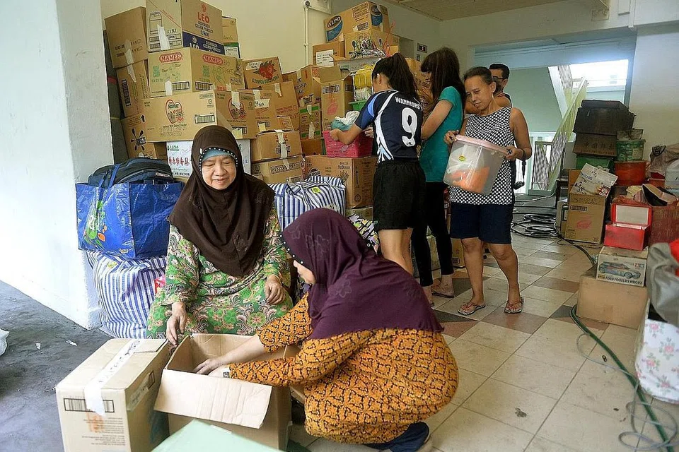 PERIKSA BARANG: Cik Saurah (berkurung hijau) serta anggota keluarganya lain sedang sibuk mengemas, meneliti dan membungkus barang yang masih boleh dipakai dan perlu dibuang. Bersamanya ialah anaknya, Cik Zaini Mohamad (duduk), Cik Zalinda Mohamad (mengangkat bekas), Cik Lina Mohamad (berbaju hijau) dan cucu Mira Zaffira Mahmood (memakai jersi). - Foto KHALID BABA