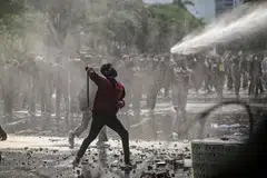Seorang penunjuk perasaan melontar barang semasa bertembung dengan polis di Surabaya pada 24 Mac.