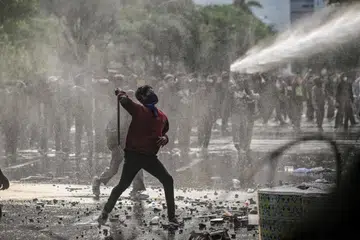 Seorang penunjuk perasaan melontar barang semasa bertembung dengan polis di Surabaya pada 24 Mac.