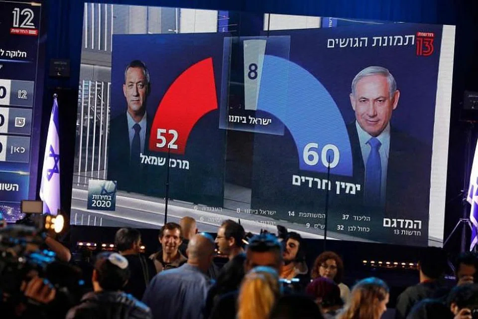 Orang ramai menyaksikan siaran televisyen Channel 13 yang menyiarkan ramalan selepas pengundian ditutup dalam pilihanraya Israel pada 2 Mac. 