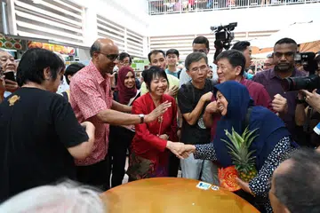 BERAMAH MESRA DENGAN PENDUDUK: Encik Tharman Shanmugaratnam dan isterinya, Cik Jane Ittogi bertemu dan berjabat tangan bersama penduduk di Pusat Penjaja Taman Jurong pada pagi Selasa.