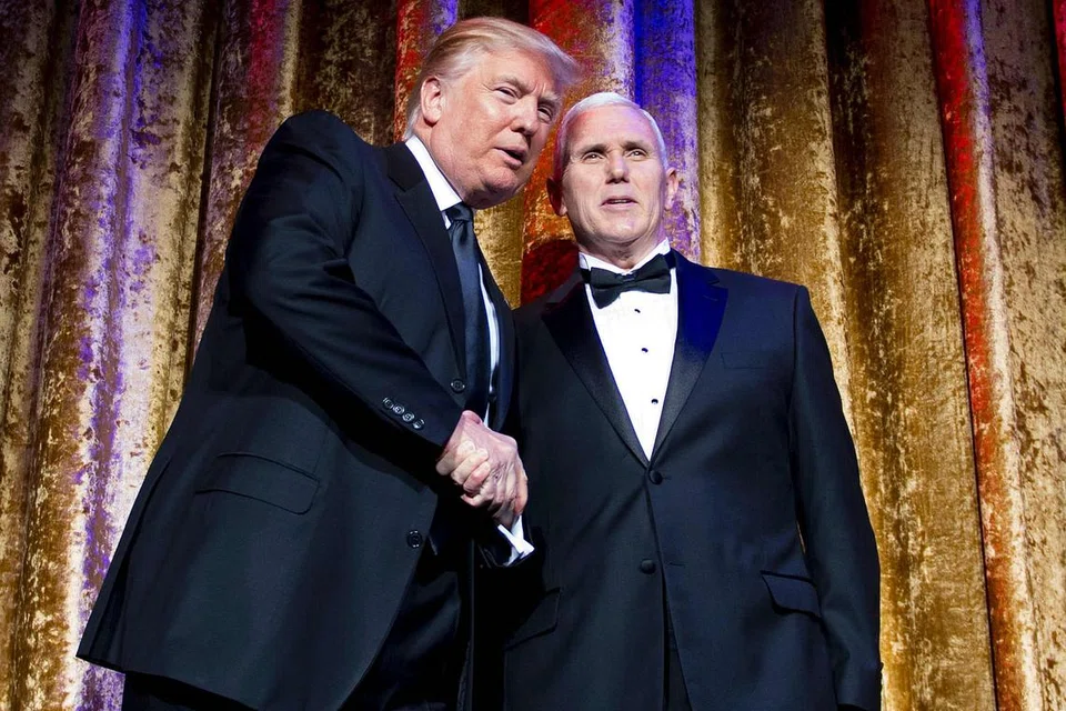 TERUS JADI TUMPUAN: Encik Donald Trump (kiri) berjabat tangan dengan bakal Naib Presiden, Encik Mike Pence, sedang mereka menghadiri Jamuan Makan Malam bagi meraikan diplomat-diplomat asing di Washington DC. - Foto AFP