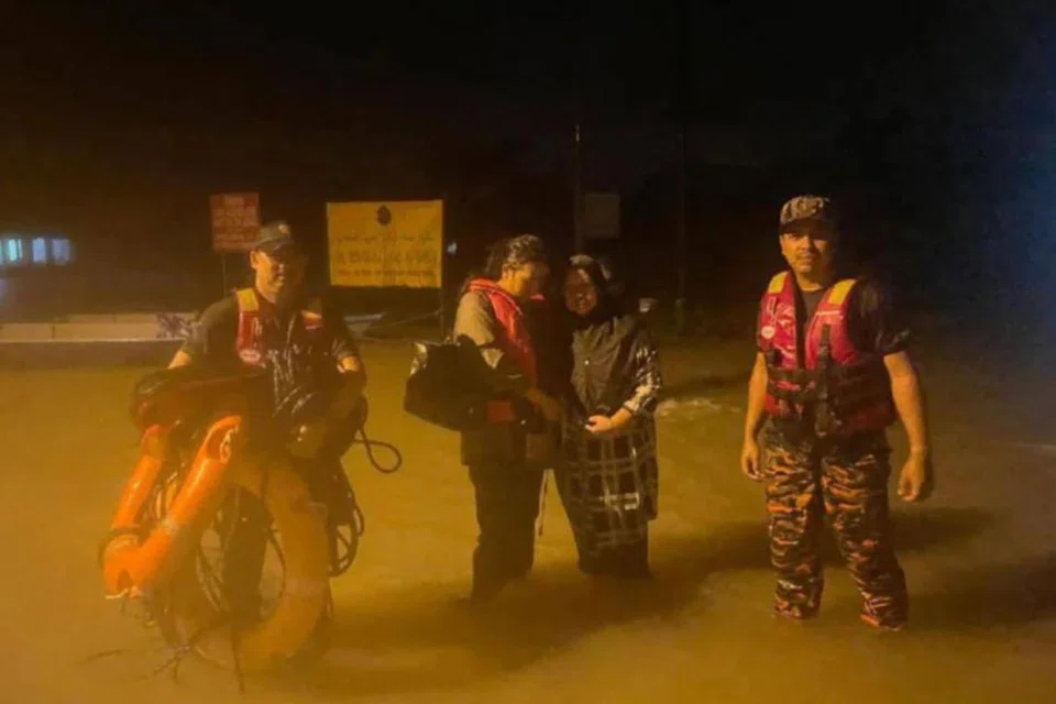 Dua beranak (tengah) berpaut pada pokok selama lima jam selepas perahu yang mereka naiki untuk menyelamatkan diri daripada banjir dipukul arus deras, sebelum diselamatkan anggota bomba di Kampung Tasek, Lubok Gong, Rantau Panjang, Kelantan.