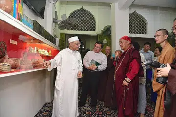KONGSI PENGETAHUAN: Imam Masjid Ba'alwie, Habib Syed Hassan Al-Attas (kiri) menunjukkan artifak dunia Islam yang dipamerkan di masjid itu kepada Master Hsin Tao (baju merah) dan tetamu lain. - Foto BH oleh DESMOND WEE