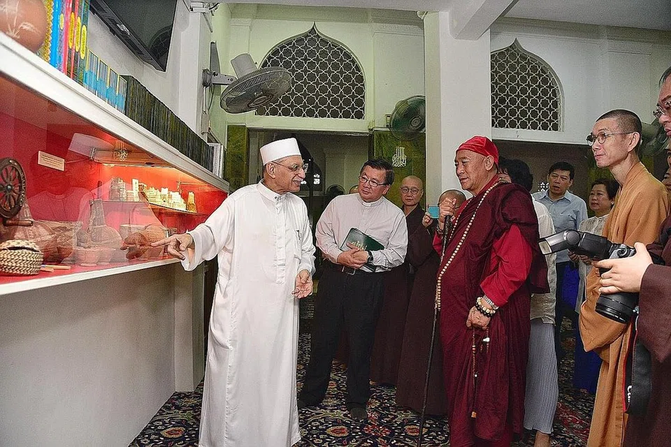 KONGSI PENGETAHUAN: Imam Masjid Ba'alwie, Habib Syed Hassan Al-Attas (kiri) menunjukkan artifak dunia Islam yang dipamerkan di masjid itu kepada Master Hsin Tao (baju merah) dan tetamu lain. - Foto BH oleh DESMOND WEE