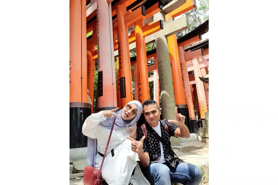 GAMBAR KENANGAN: Penulis dan isteri bergambar di Kuil Fushimi Inari di Kyoto yang terkenal dengan gerbang-gerbang berwarna oren yang mengelilingi kompleks agama Shinto dan diiktiraf sebagai warisan dunia Unesco. - Foto BH oleh NAZRY MOKHTAR