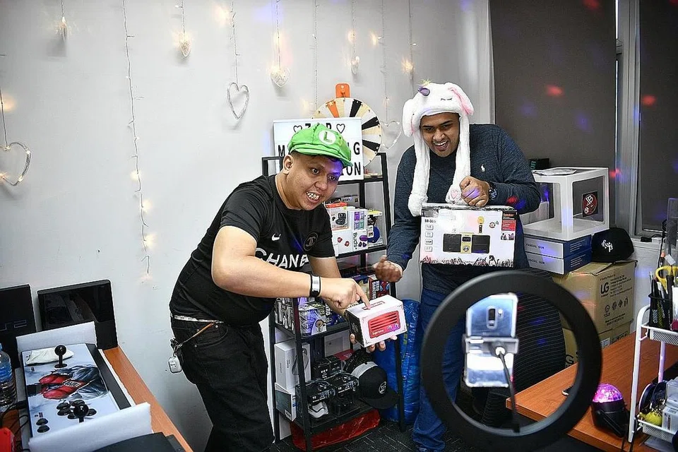 ZAX RAMLI: Zax (kiri) pelajari teknik lelong barangan dalam talian bersama rakannya, Md Shariff S/O Md Yusoof (Mama Sachok) sebagai cara menambah rezeki. - Foto BH oleh ARIFFIN JAMAR