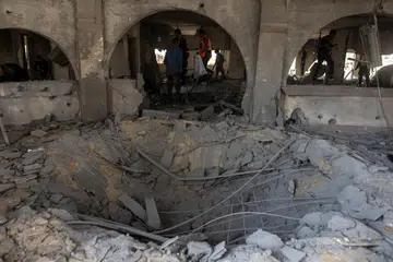 Penduduk Palestin memeriksa kesan kemusnahan akibat serangan udara Israel yang menyasarkan ibu pejabat Kementerian Dalam Negeri yang dikendalikan Hamas di Khan Younis, selatan Gaza, pada 2 Januari. 