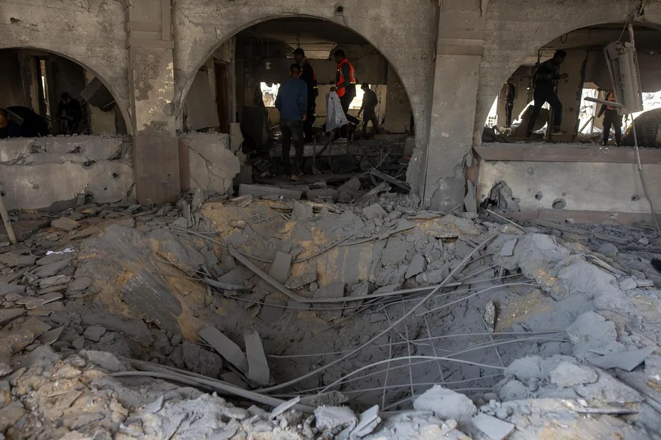 Penduduk Palestin memeriksa kesan kemusnahan akibat serangan udara Israel yang menyasarkan ibu pejabat Kementerian Dalam Negeri yang dikendalikan Hamas di Khan Younis, selatan Gaza, pada 2 Januari. 