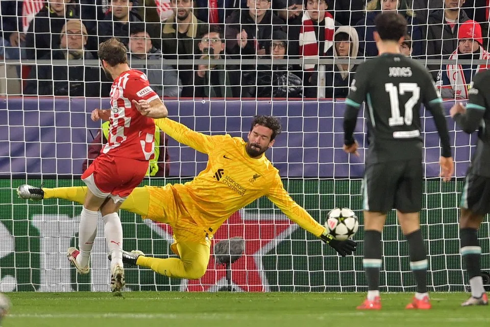 Rembatan pemain pertahanan Girona, Daley Blind (kiri), dihalang penjaga gol Liverpool, Alisson Becker, dalam perlawanan Liga Juara-Juara di Stadium Montilivi di Girona pada 10 Disember 2024. 