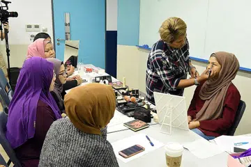 KONGSI ILMU BERSOLEK: Pelajar jurusan perniagaan Politeknik Temasek, Cik Nor Umairah Mohd Ishak (sedang disolek), mendapat sentuhan solekan daripada jurusolek mapan, Cik Fatimah Mohsin, semasa kursus solekan pengantin yang diadakan di bawah SkillsFuture@PA Oktober lalu. - Foto PA