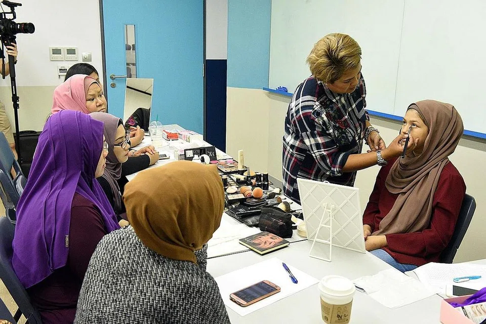 KONGSI ILMU BERSOLEK: Pelajar jurusan perniagaan Politeknik Temasek, Cik Nor Umairah Mohd Ishak (sedang disolek), mendapat sentuhan solekan daripada jurusolek mapan, Cik Fatimah Mohsin, semasa kursus solekan pengantin yang diadakan di bawah SkillsFuture@PA Oktober lalu. - Foto PA