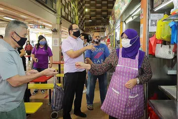 DEKATI PEGERAI: Menteri Perhubungan dan Penerangan Encik S Iswaran (tengah) mendapatkan maklum balas dari pemilik Gerai Makanan Hani, Encik Mohd Zairuddin Onan (dua dari kanan) dan adik iparnya, Cik Nor Izwani bte Ismail (paling kanan) , di pasar West Coast. Duta Pejabat Digital SG (SDO), sedang berusaha mendekati pemilik gerai supaya mempercepat penggunaan digital di kalangan masyarakat. - Foto Gavin Foo