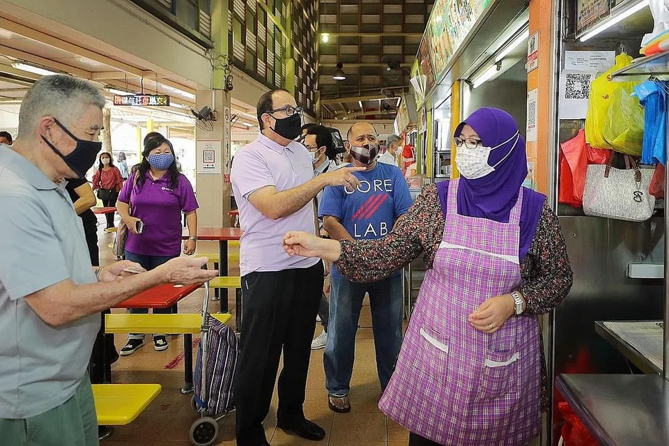 DEKATI PEGERAI: Menteri Perhubungan dan Penerangan Encik S Iswaran (tengah) mendapatkan maklum balas dari pemilik Gerai Makanan Hani, Encik Mohd Zairuddin Onan (dua dari kanan) dan adik iparnya, Cik Nor Izwani bte Ismail (paling kanan) , di pasar West Coast. Duta Pejabat Digital SG (SDO), sedang berusaha mendekati pemilik gerai supaya mempercepat penggunaan digital di kalangan masyarakat. - Foto Gavin Foo