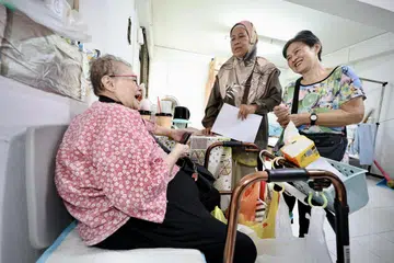 BERI SOKONGAN: Cik Sapiah Ahmad (tengah) bersama temannya, Cik Lee Boo Than (kanan), melakukan lawatan ke rumah warga emas di Blok 61 Geylang Bahru.