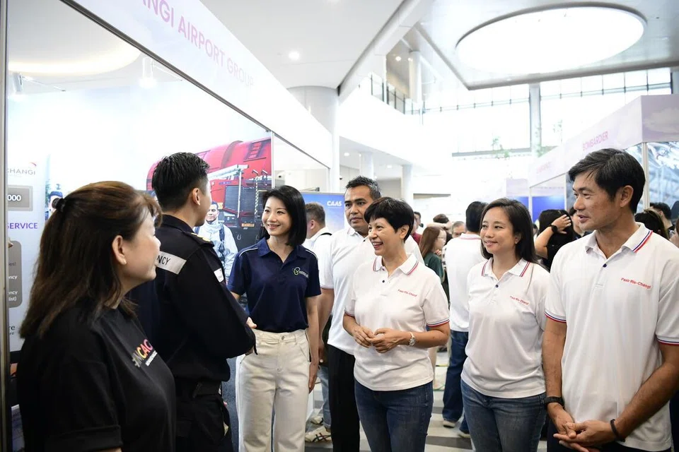 Menteri Negara Kanan Pengangkutan merangkap Pembangunan Negara, Cik Sun Xueling (tiga dari kiri); Penasihat Akar Umbi GRC Pasir Ris-Changi, Encik Sharael Taha (empat dari kiri); Menteri di Pejabat Perdana Menteri merangkap Menteri Kedua Kewangan dan Pembangunan Negara, Cik Indranee Rajah (tiga dari kanan); serta Penasihat Akar Umbi GRC Pasir Ris-Changi, Cik Valerie Lee (dua dari kanan) dan Encik Desmond Tan (kanan), berinteraksi dengan seorang majikan semasa pameran North East OneAviation Careers 2026.