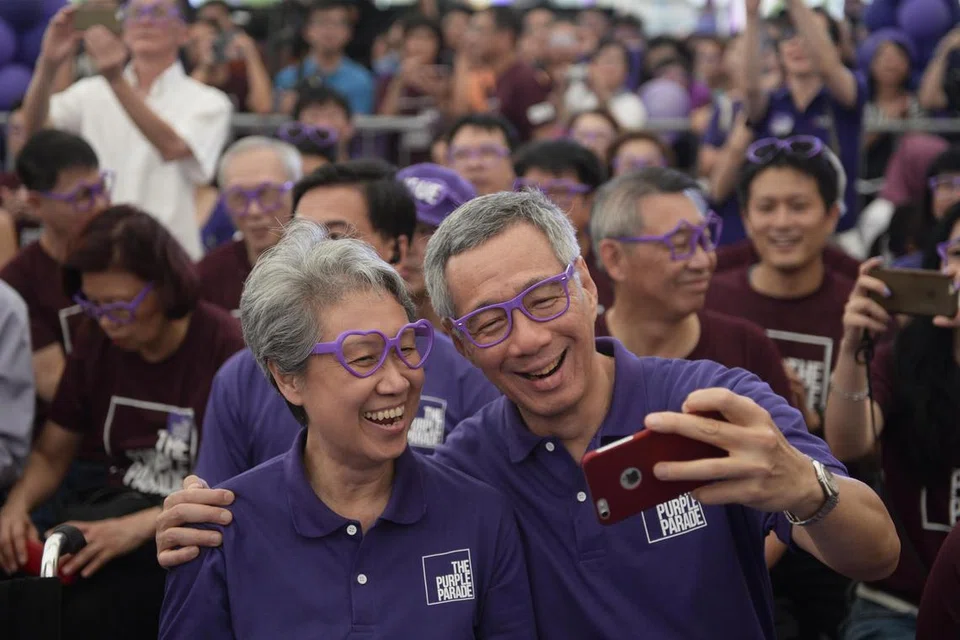 Encik Lee Hsien Loong (kanan) dan isteri, Cik Ho Ching (kiri), bergambar bersama semasa menyertai acara The Purple Parade pada 2015. Acara itu meraikan inklusiviti dan individu kurang upaya.