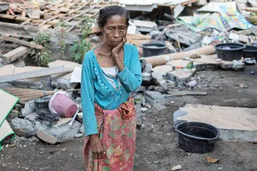 SUGUL: Seorang penduduk kampung Labu Pandan mengenangkan nasib memandangkan rumahnya habis ranap ekoran gempa yang melanda Lombok baru-baru ini. - Foto AFP