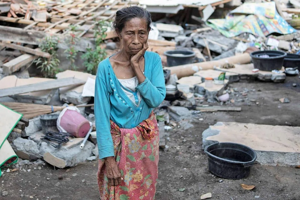 SUGUL: Seorang penduduk kampung Labu Pandan mengenangkan nasib memandangkan rumahnya habis ranap ekoran gempa yang melanda Lombok baru-baru ini. - Foto AFP