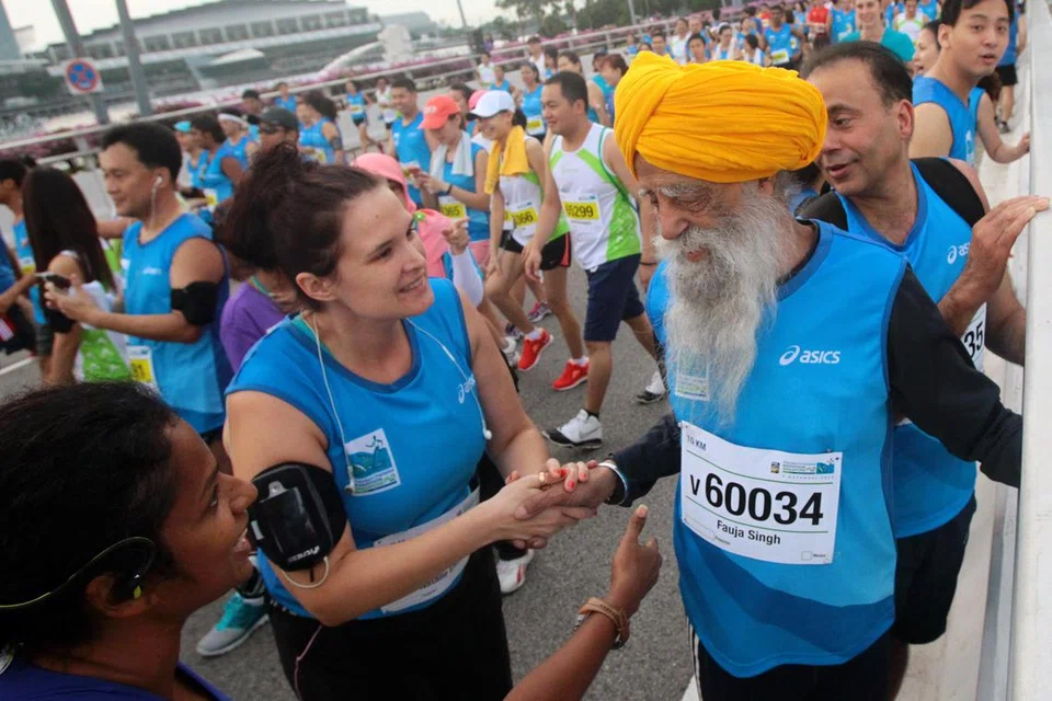 Pelari maraton pemecah rekod, Fauja Singh (kanan), yang berusia 101 tahun, bersalaman dengan para peminat sebelum memulakan larian 10km di Standard Chartered Marathon Singapura pada 2 Disember 2012. Beliau mengambil masa satu jam setengah untuk menamatkan laluan tersebut.
