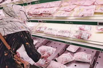 BELI AYAM: Seorang wanita dilihat di NTUC FairPrice di Woodlands memilih ayam segar untuk dibeli.