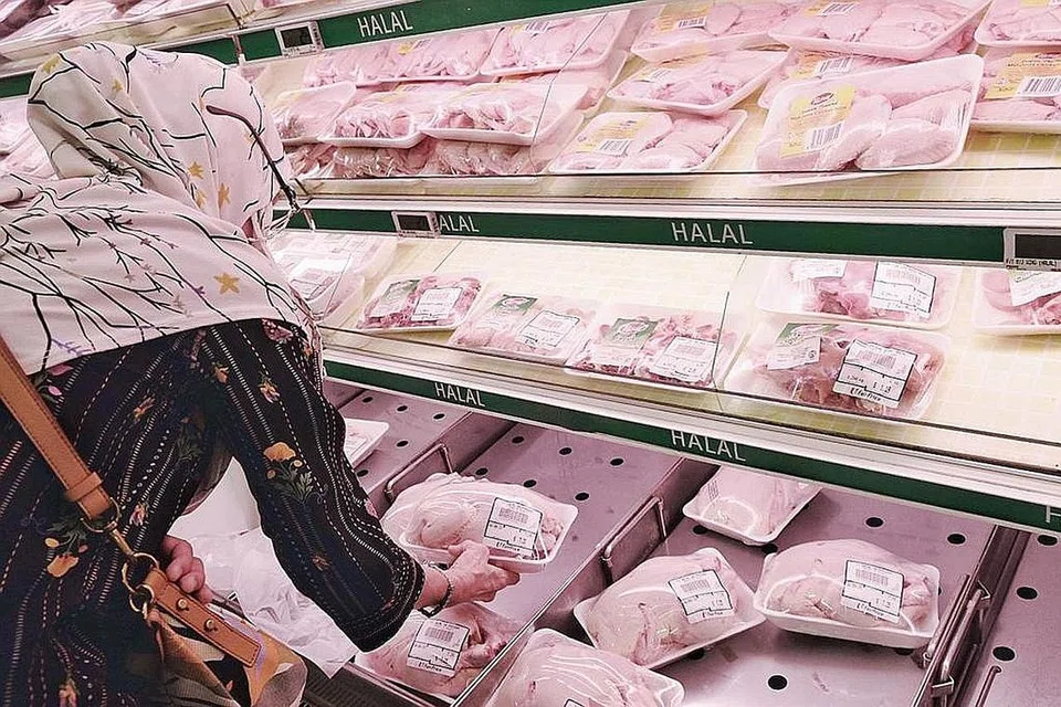 BELI AYAM: Seorang wanita dilihat di NTUC FairPrice di Woodlands memilih ayam segar untuk dibeli.