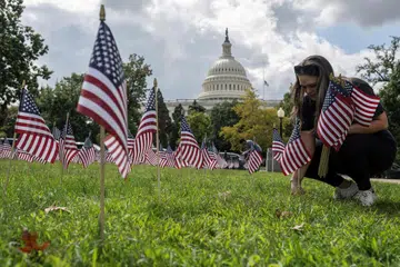 Seorang wanita menanam bendera sempena peringatan 9/11 yang dianjurkan oleh Yayasan Amerika Muda, di luar Bangunan Capitol Amerika Syarikat di Washington, DC pada 11 September 2025, bersempena ulang tahun ke-24 serangan 9/11. New York pada hari yang sama turut memperingati tragedi dahsyat 11 September 2001, 24 tahun selepas rampasan pesawat yang meragut hampir 3,000 nyawa dan mengubah Amerika Syarikat untuk selama-lamanya.