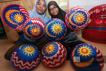 Cik Salmila (kiri) dibantu anak perempuannya, Nor Syafiqah bersama tudung saji bercorakkan Jalur Gemilang yang ditempah pelanggan mereka sempena Hari Kemerdekaan ke-67 ketika ditemui di Bandar Putra Bertam, Kepala Batas.