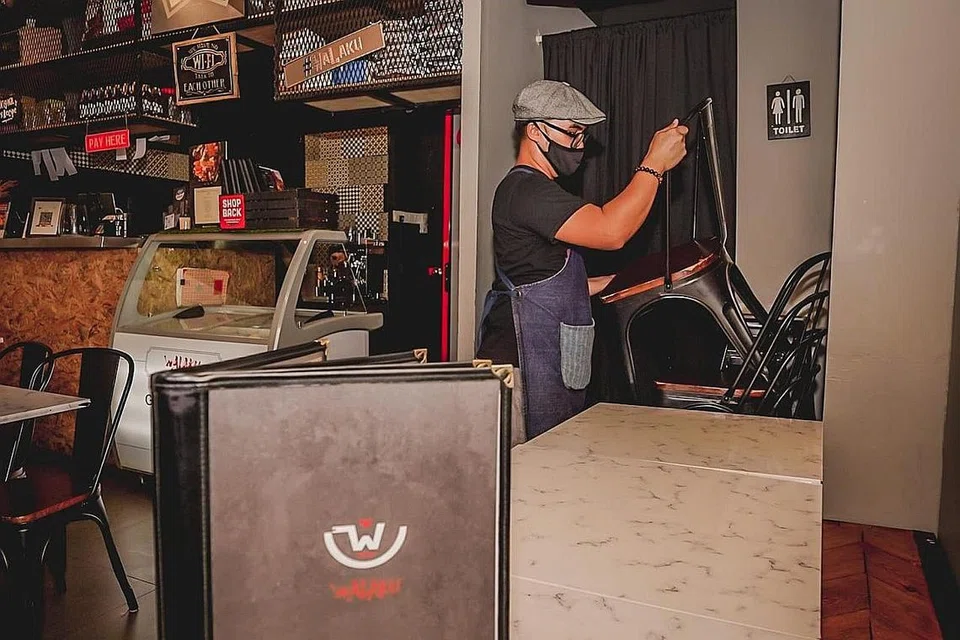 BERKEMAS: Kakitangan restoran Walaku yang terletak di Joo Chiat Road mengalihkan kerusi dan membuat persiapan sedang Singapura kembali ke Fasa Dua (Kewaspadaan Dipertingkat) di mana kegiatan menjamu selera di cawangan F&B tidak dibenarkan. - Foto BH oleh NUR DIYANA TAHA