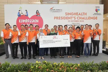 KUMPUL DANA: Cik Rahayu Mahzam (tujuh dari kiri) dan Presiden Halimah (bertudung hijau) menerima cek lebih $1.2 juta bagi Cabaran Presiden semalam oleh SingHealth. - Foto BM oleh ALPHONSUS CHERN