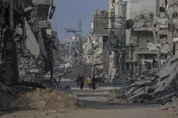 Rakyat Palestin berjalan melepasi bangunan yang musnah ketika mereka kembali ke Khan Younis selepas tentera Israel menarik keluar tentera dari selatan Jaluran Gaza, pada 30 April. Menurut Pertubuhan Bangsa-Bangsa Bersatu (PBB), ia akan mengambil masa bertahun-tahun untuk membersihkan sekitar 23 juta tan runtuhan dan senjata tidak meletup senjata yang kini bertaburan di seluruh Gaza.