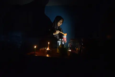 Seorang penjual menyediakan minuman untuk pelanggan ketika gangguan bekalan elektrik di Nagari Kasang, Padang Pariaman, Sumatera Barat.