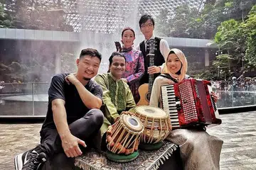 GIAT BERGABUNG: Cik Syafiqah Adha Mohamed Sallehin (kanan) giat berkolaborasi bersama pemuzik pelbagai budaya dan latar belakang. Dalam gambar, Cik Syafiqah bersama kumpulan GIMA band dan pemain tabla Nawaz Mirajkar sewaktu perakaman video muzik khas untuk Hari Keharmonian Kaum pada 2019. - Foto ihsan SYAFIQAH ADHA MOHAMED SALLEHIN