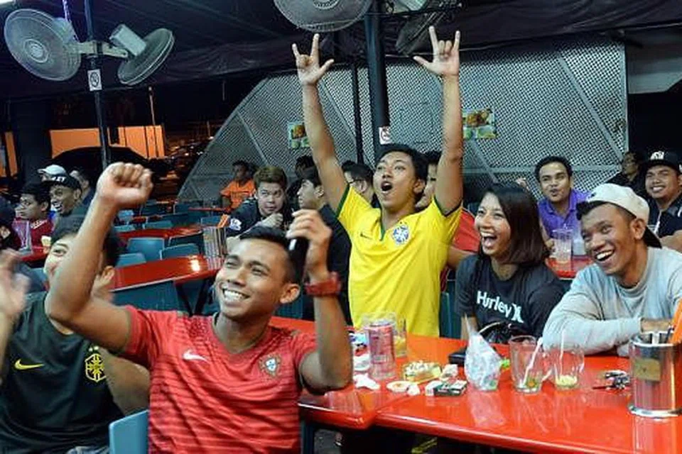 GOL!: Penyokong di restoran Enak-Enak Hongkong Tea House di Simpang Bedok meraikan gol terakhir Brazil. Beberapa pusat makanan yang berhampiran juga menayangkan perlawanan bola sepak antara Brazil dan Croatia.