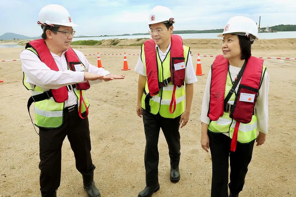 DIBERI PENERANGAN: Encik Wong (tengah) diberi taklimat mengenai projek penambakan Pulau Tekong yang bakal menambah keluasan tanah baru seluas dua kejiranan Toa Payoh. - Foto THE STRAITS TIMES