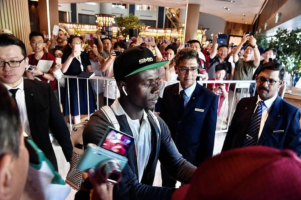 SAMBUTAN MERIAH: Para peminat Liverpool yang telah berkumpul di hotel Swissotel The Stamford kelmarin memberikan sorakan yang gemuruh sejurus Sadio Mane (kiri) tiba di hotel itu. - Foto BH oleh DESMOND FOO