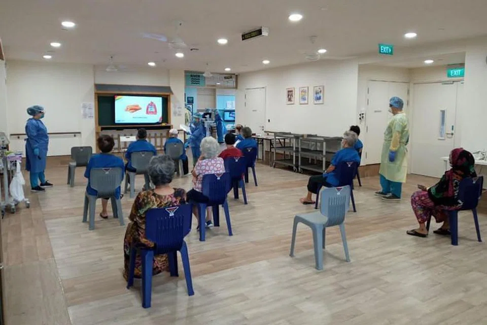 Kakitangan berinteraksi dengan pesakit warga emas dalam kegiatan di kemudahan rawatan masyarakat Covid-19 baru di Tampines.