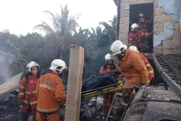 Pasukan bomba membawa keluar mangsa yang ditemui rentung di sebuah rumah di Pitas, Sabah.