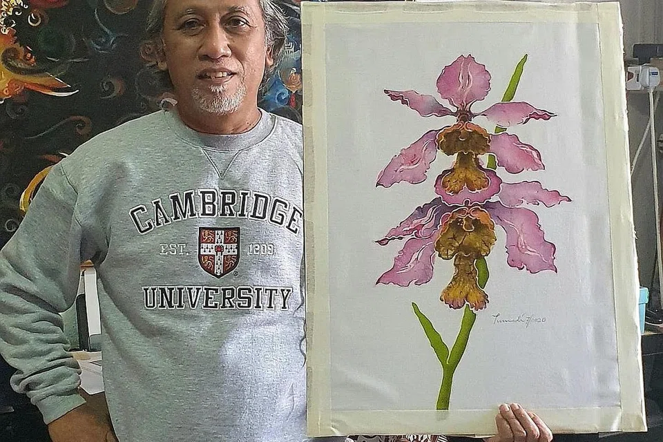 PAMER KARYA SENI: Encik Tumadi Patri bersama karya lukisan bunga orkid berteraskan elemen batik yang menjadi identitinya. - Foto ihsan TUMADI PATRI