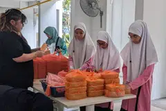 Pelajar Madrasah Al-Ma’arif membungkus dan mengagihkan bubur kepada penduduk yang memerlukan di kawasan Marine Parade pada 14 Mac lalu. 