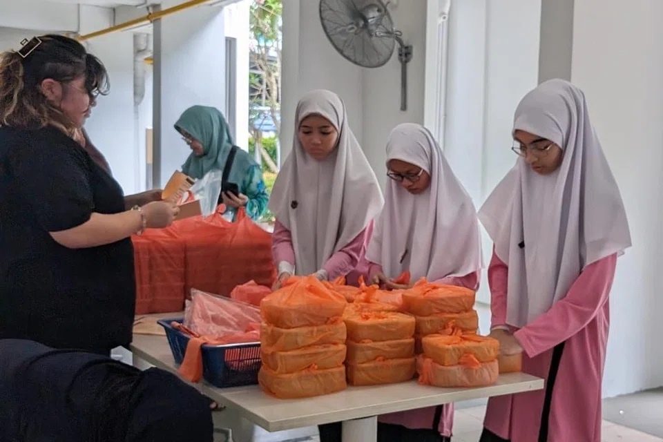 Pelajar Madrasah Al-Ma’arif membungkus dan mengagihkan bubur kepada penduduk yang memerlukan di kawasan Marine Parade pada 14 Mac lalu. 
