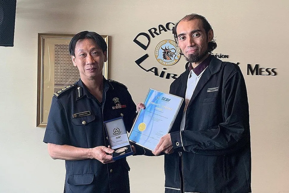 'WIRA' STESEN MRT: Encik Mohamed Ferdaus Mohamed Yusoff (kanan) menerima anugerah Penyelamat Masyarakat Pasukan Pertahanan Awam Singapura (SCDF) daripada Kolonel Lim Boon Hwee setelah menyelamatkan budak yang hampir terjatuh dari tangga bergerak setinggi kira-kira lima meter. - Foto BH oleh HAZIRAH NURFITRAH HANIFAR