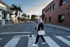 LENGANG: Seoramg wanita melintasa jalan di Long Beach, California kelmarin. Presiden Donald Trump telah melanjutkan perintah arahan pergerakan. - Foto AFP