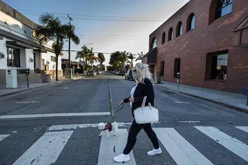 LENGANG: Seoramg wanita melintasa jalan di Long Beach, California kelmarin. Presiden Donald Trump telah melanjutkan perintah arahan pergerakan. - Foto AFP