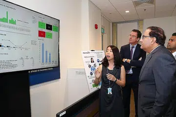 GUNAKAN ANALITIK DATA: Encik Iswaran (kanan) melihat skrin yang menunjukkan analitik data di Pusat-E Singapura P&G. - Foto ZAOBAO