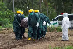 Pekerja mengusung jenazah pesakit Covid-19 untuk dikebumikan di Pulau Sangihe, di Utara Sulawesi.