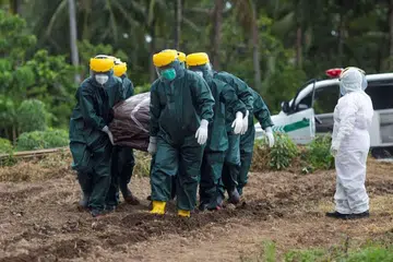 Pekerja mengusung jenazah pesakit Covid-19 untuk dikebumikan di Pulau Sangihe, di Utara Sulawesi.