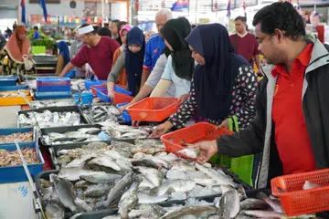 Pelanggan membeli ikan di sebuah pasar di Johor Bahru.