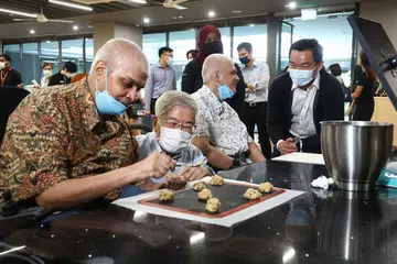 TERUS BERDIKARI: Encik Mohamed Akhbar, 53 tahun (paling kiri), dan adiknya, Encik Mohamed Ashraf Mohd Yusof, 50 tahun (dua dari kanan) - kededuanya pesakit Cerebral Palsy - menjalani latihan di pusat khidmat sosial AWWA yang lengkap dengan kemudahan untuk golongan orang kurang upaya (OKU). Mereka ditemani Encik Gan (dua dari kiri) dan Encik Chua (paling kanan). - Foto LIANHE ZAOBAO
